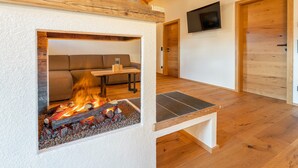 A cozy room with a fireplace, a sofa, and a TV mounted on the wall. - Luxuriously furnished penthouse (Mauterndorf)