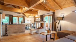 A spacious living area with wooden floors, a fireplace, and a dining area with a view of the outdoors. - Luxuriously furnished penthouse (Mauterndorf)
