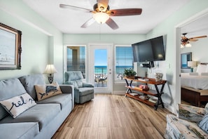 Relax in this cozy living space with a sofa, chair, and flat-screen TV, offering a view of the ocean through glass doors.