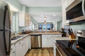 Enjoy cooking in this well-equipped kitchen with a central island, dishwasher, and stove, offering a scenic view.