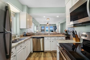 Enjoy cooking in this well-equipped kitchen with a central island, dishwasher, and stove, offering a scenic view.