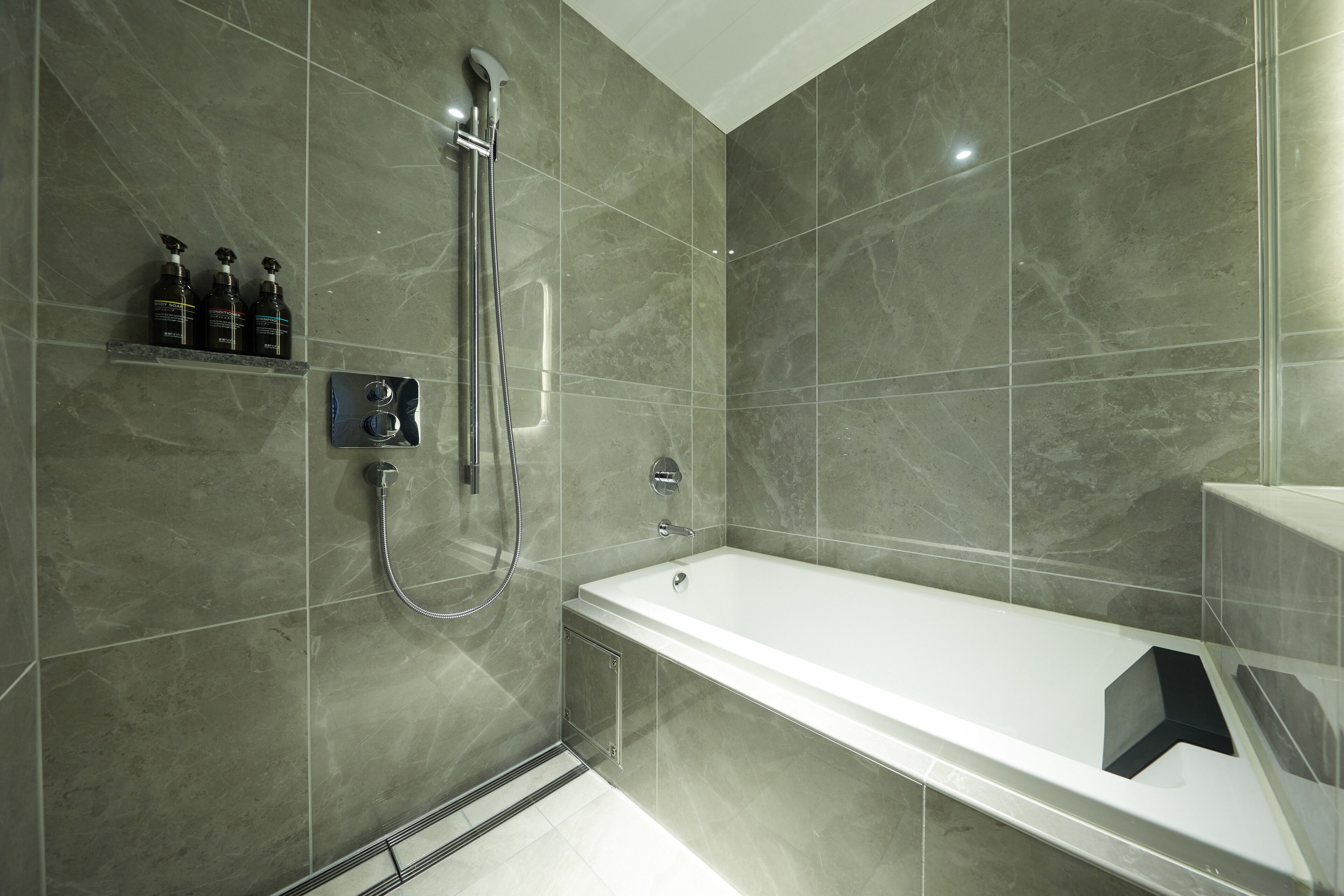 A modern bathroom with a bathtub, a shower, and a shelf with toiletries.