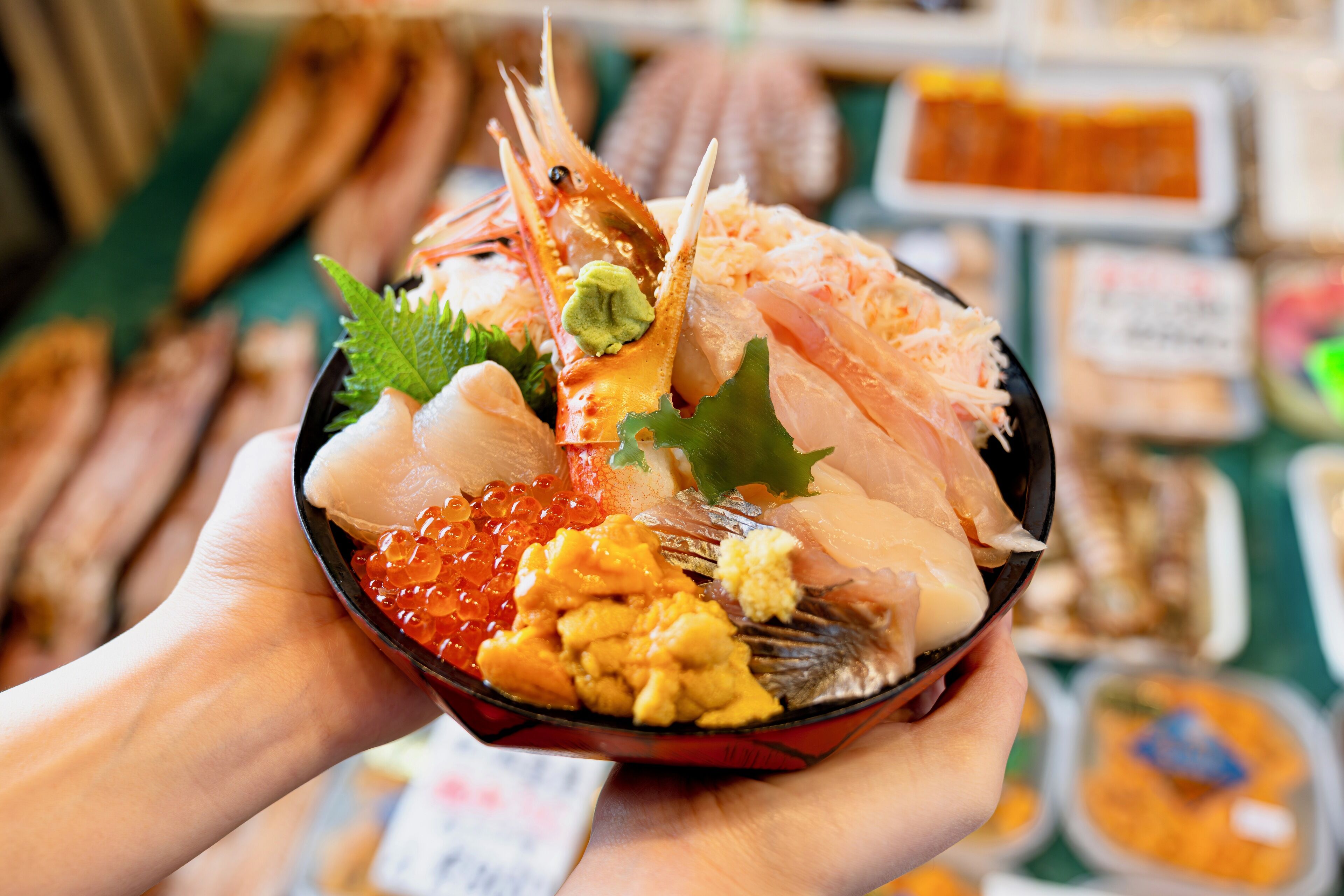 A bowl of sushi with various ingredients including fish, roe, and garnishes.