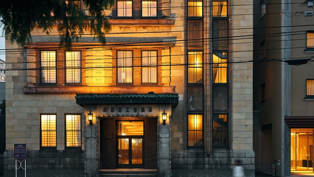 A historic building with a prominent entrance, large windows, and a signboard.