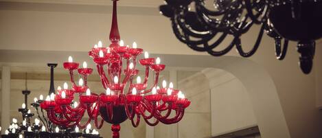 A chandelier with multiple candle-like lights in a room with arched ceilings and a mirror.