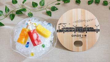 Una placa de madera con una ilustración de tren y texto, junto a un recipiente de vidrio con hielo y objetos coloridos.