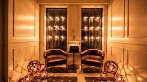 A hallway with two leather chairs, a table with a sign, and decorative spherical lights.