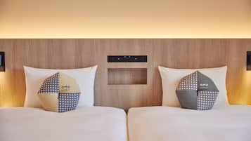 Een hotelkamer met twee bedden, elk voorzien van een kussen met een geometrisch patroon en het logo "OMO".