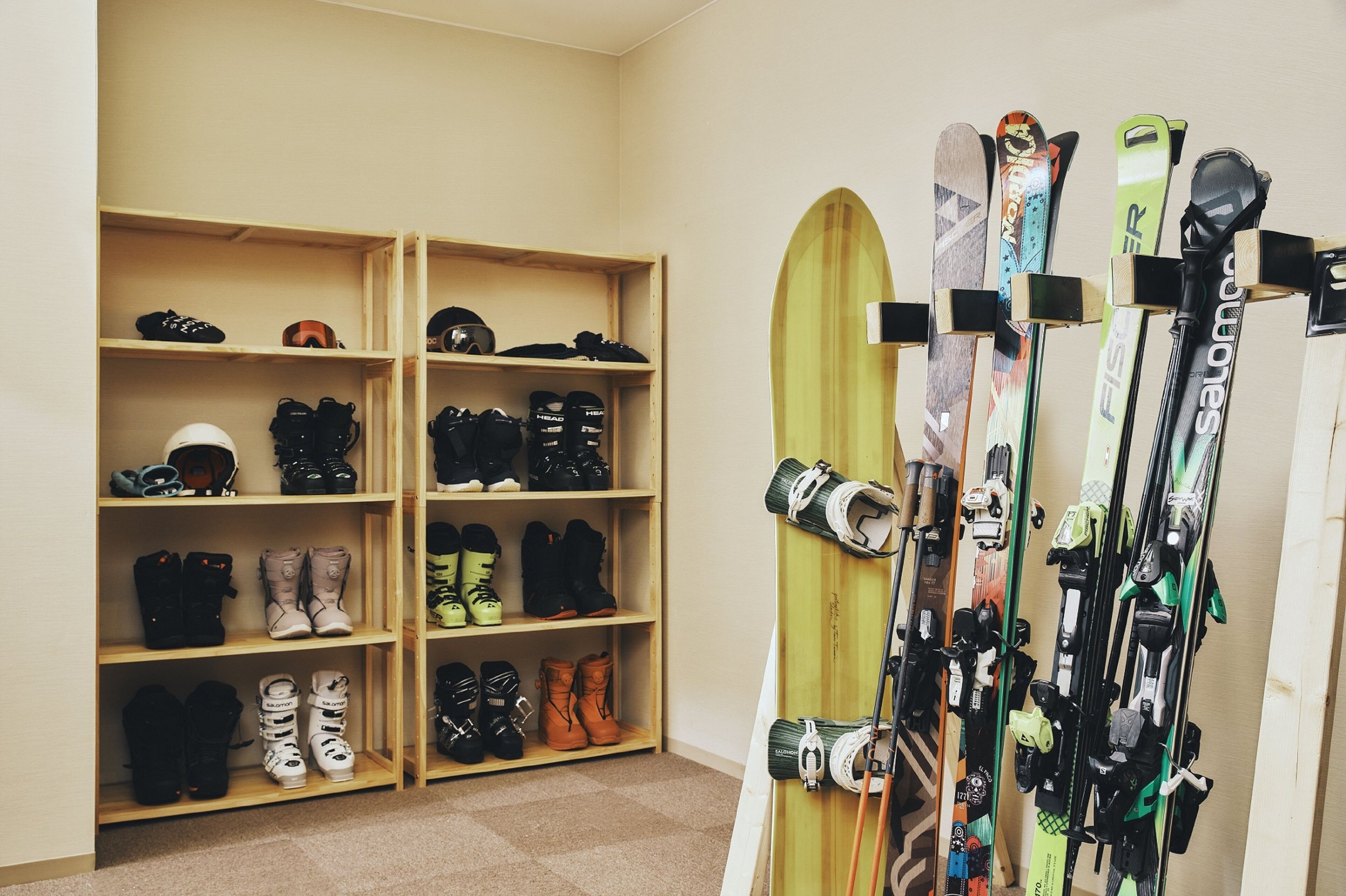Une pièce avec des étagères en bois où sont exposés différents types de chaussures et de skis.