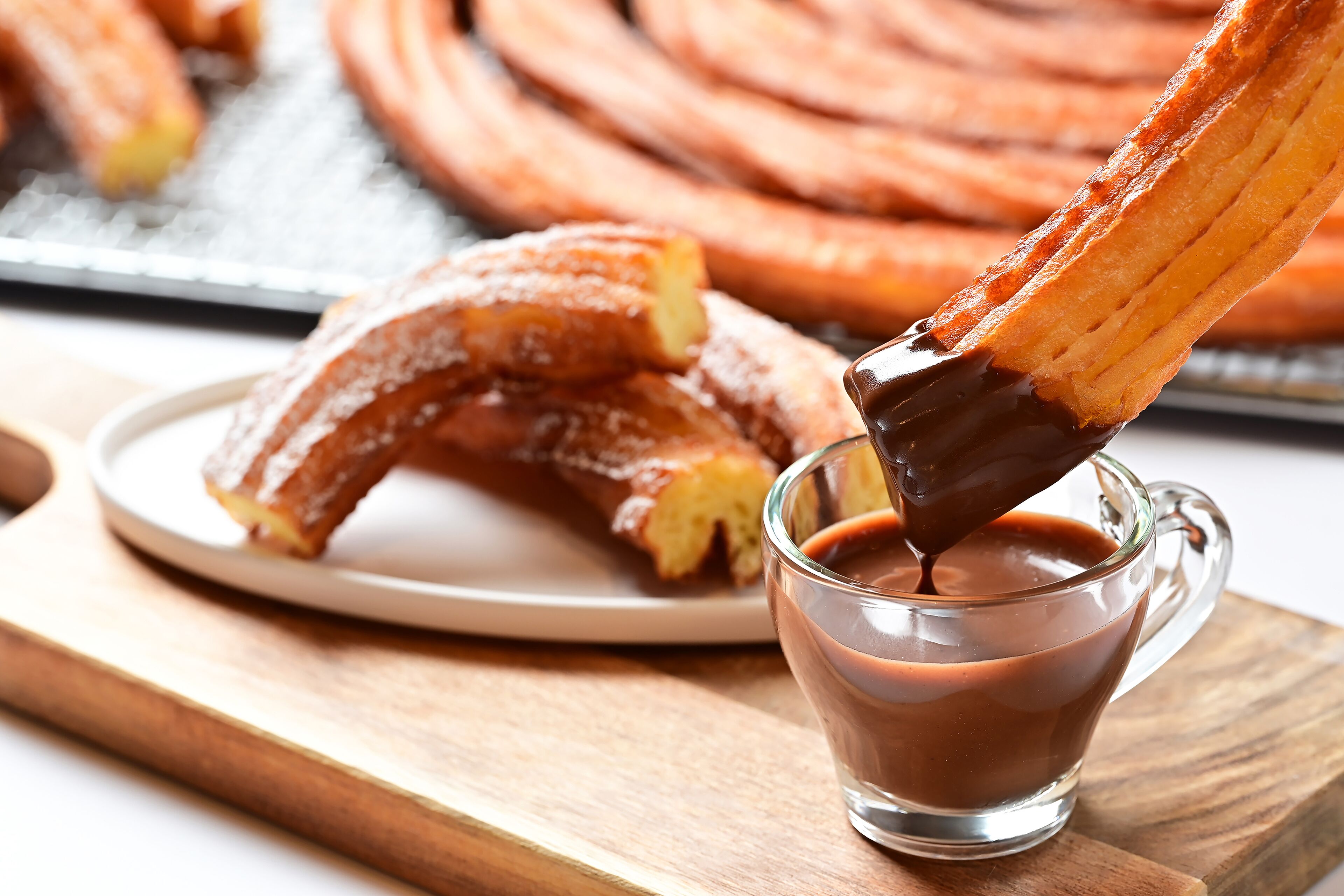 A plate of churros with chocolate sauce being poured over them.