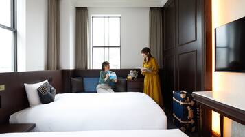 Una habitación de hotel con una cama grande, un escritorio con lámpara, una maleta y un televisor en la pared.
