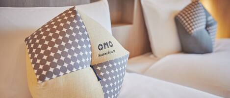 A bed with a pillow featuring a geometric pattern and the text "OMO Hashing Resorts".