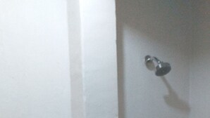 Ein Badezimmer mit beigen Fliesen, einer Toilette und einer Duschkabine.