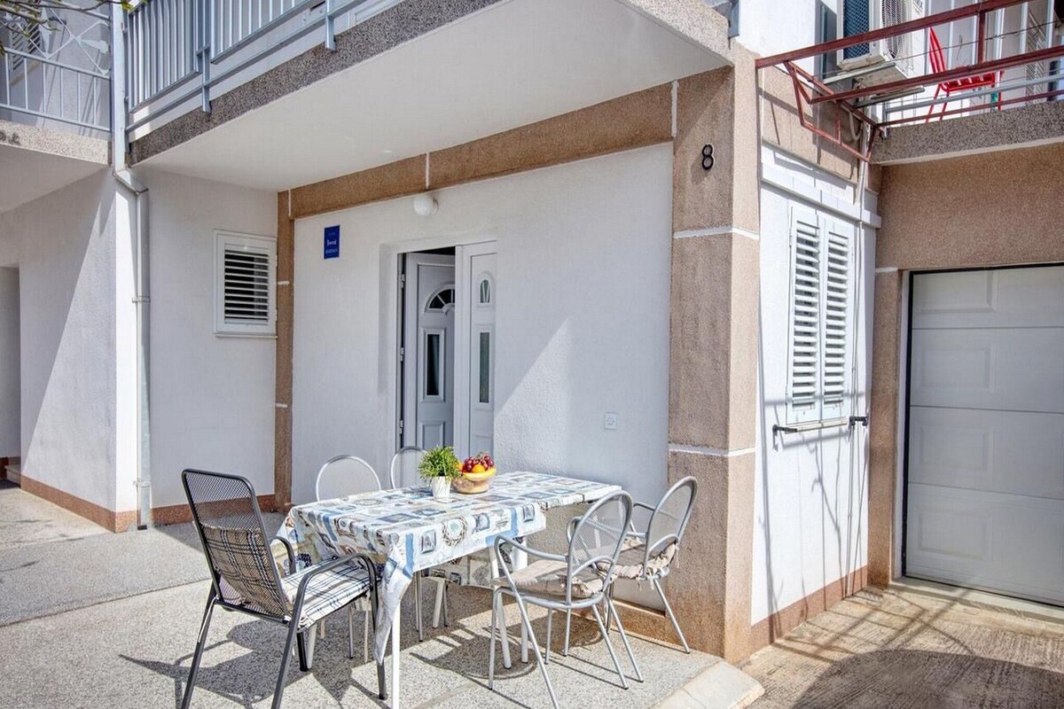 Une terrasse avec une table et des chaises, une porte et une porte de garage.