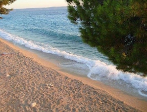 En strand med en sandstrand och vågor som försiktigt skvalpar mot kanten.