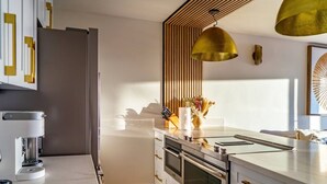 A modern kitchen with a built-in coffee maker, a stainless steel refrigerator, and a pendant light.