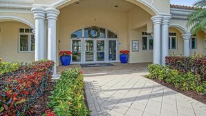 Entrada de hotel com um grande arco, uma coroa de flores na porta e plantas em vasos de ambos os lados.