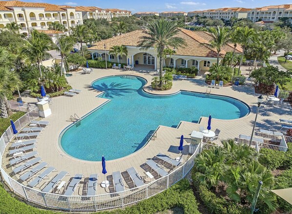 A resort with a large, curved swimming pool surrounded by lounge chairs and umbrellas.