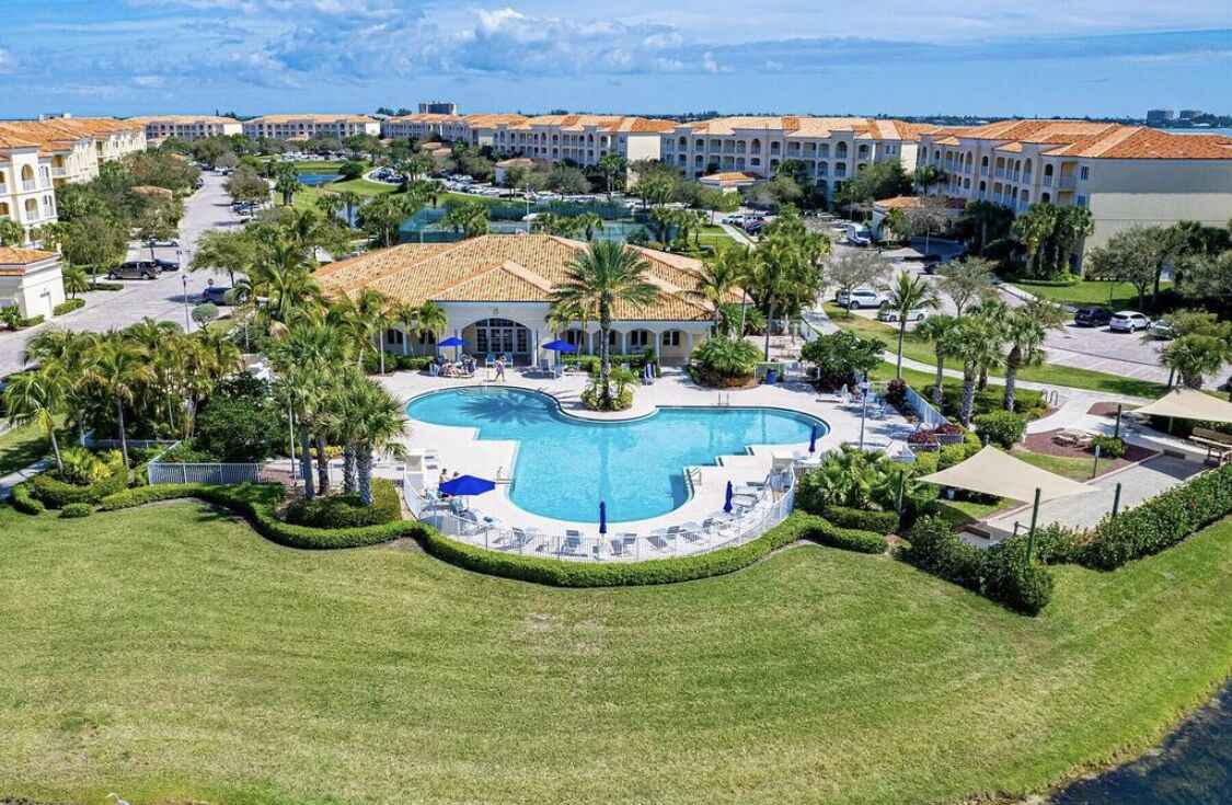 Ein Resort mit einem zentralen Schwimmbad, mehreren Gebäuden mit roten Ziegeldächern und einer gepflegten Rasenfläche.