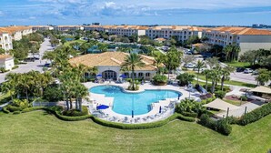 Resort com piscina central, vários edifícios com telhados em tijolo vermelho e um jardim bem cuidado.
