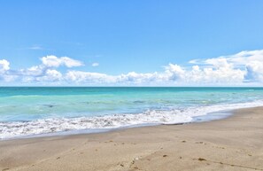 Ein Strand mit klarem türkisblauem Wasser und einem Sandufer.