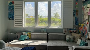 Quarto com uma grande janela, sofá e várias decorações nas paredes.