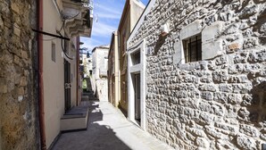 Uma rua estreita com edifícios de pedra, uma escadaria visível e um céu claro.