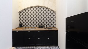Uma cozinha compacta com bancada preta, pia e micro-ondas.
