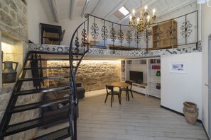 A multi-level room with a staircase, a chandelier, a television, and a bookshelf. - ★★★★★ [MODICA/Historic Center] Exclusive loft built with local stone (Modica)
