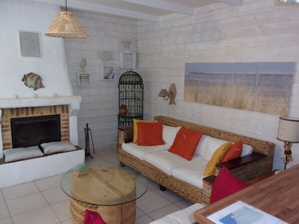 A cozy living room with a fireplace, wicker furniture, and decorative wall art.