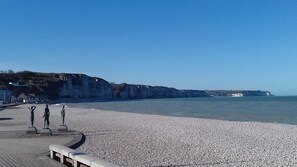 A pebble beach with a promenade, cliffs, and a clear sky. - Ocean view, patio. Sleeping arrangements for 4. (Fécamp)