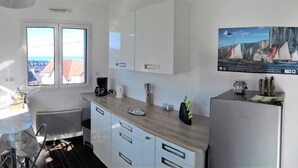 A modern kitchen with a view of the sea, a poster on the wall, and a refrigerator. - Sea view, terrace. Sleeps 4. (Fécamp)