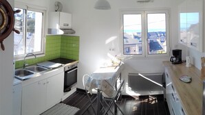 A compact kitchen with a sink, stove, and a dining area with a chair. - Sea view, terrace. Sleeps 4. (Fécamp)