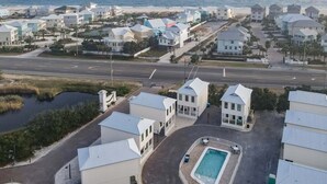 A coastal residential area with houses, a road, and a beach in the background. - ADORABLE 2 BEDROOM BEACH COTTAGE DIRECTLY ACROSS FROM BEACH! (Orange Beach)