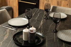 Une table à manger dressée avec des assiettes, des verres, des bougies et des couverts.