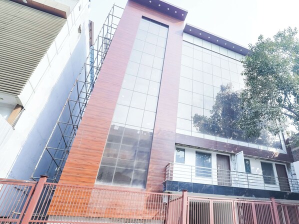 Un edificio moderno con fachada de vidrio amplia, panel de madera vertical y una cerca metálica al frente.