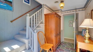 Eine Treppe mit Holzgeländer, ein Holzstuhl, ein Schrank und ein Tisch mit Lampe.