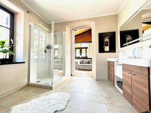Une salle de bain moderne avec une douche en verre, un tapis blanc et moelleux, et des meubles en bois.