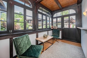 A conservatory with large windows, a wooden ceiling, and green upholstered chairs. - Stadvilla Belle Kitz (Kitzbühel)