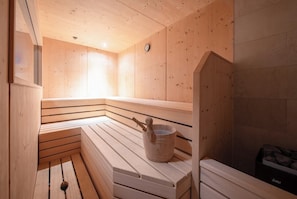 A wooden sauna with benches and a bucket. - Stadvilla Belle Kitz (Kitzbühel)