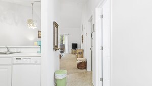 A bright, white interior with a kitchen area, a dining table, and a television in the background.