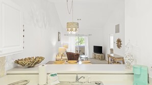 A modern kitchen with a central island, stainless steel sink, and a hanging light fixture.