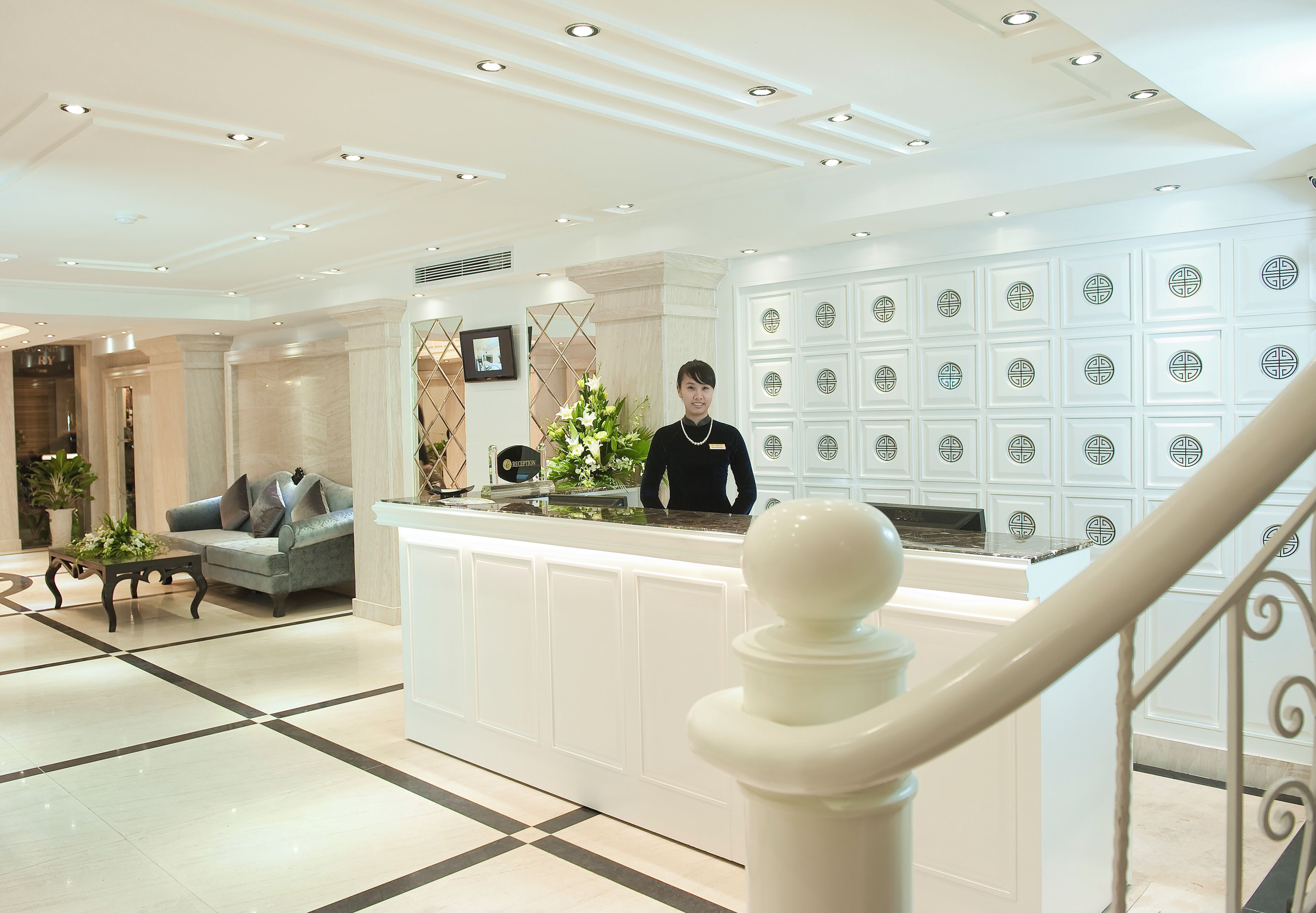 Un hall de hotel con una recepción, un sofá y una escalera.