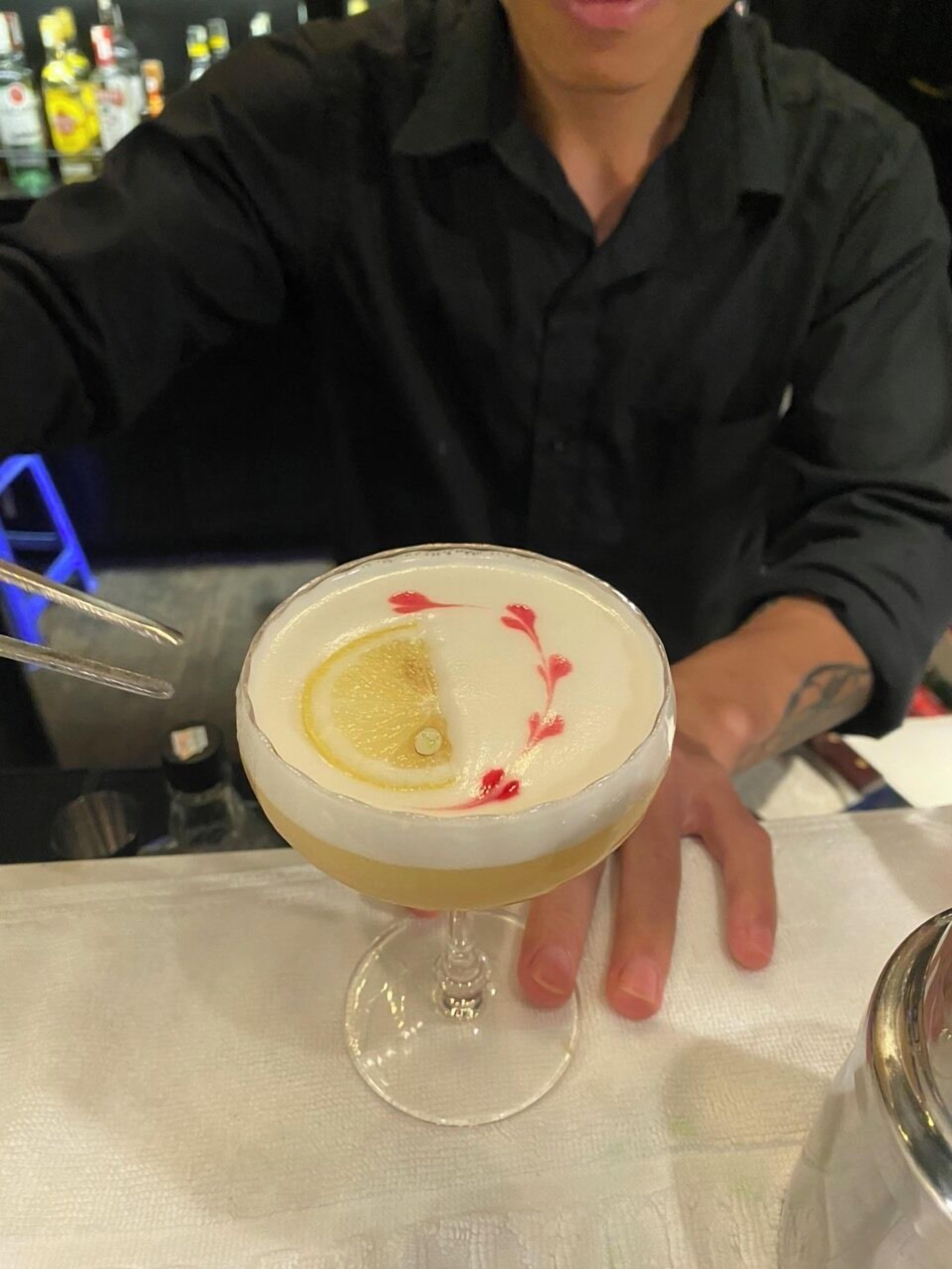 A cocktail with a lemon slice garnish in a glass.