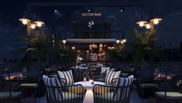 An outdoor seating area with tables and chairs, a bar in the background, and palm trees. - Victor Gallery Hotel & Spa (Hanoi)