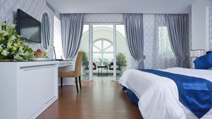 A modern hotel room with a large bed, a desk with a TV, and a balcony with a view. - Victor Gallery Hotel & Spa (Hanoi)