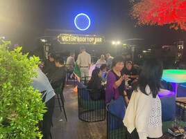 An outdoor bar area with a neon sign reading "VICTOR ROOFTOP BAR".