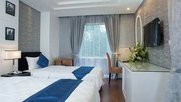 A hotel room with two beds, a desk with a mirror, and a window with curtains.