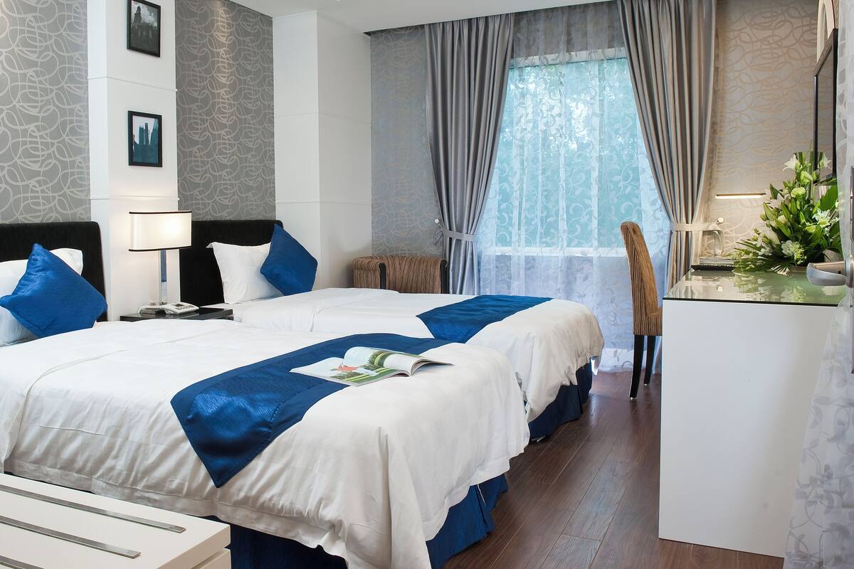 A hotel room with two beds, a desk, and a chair.