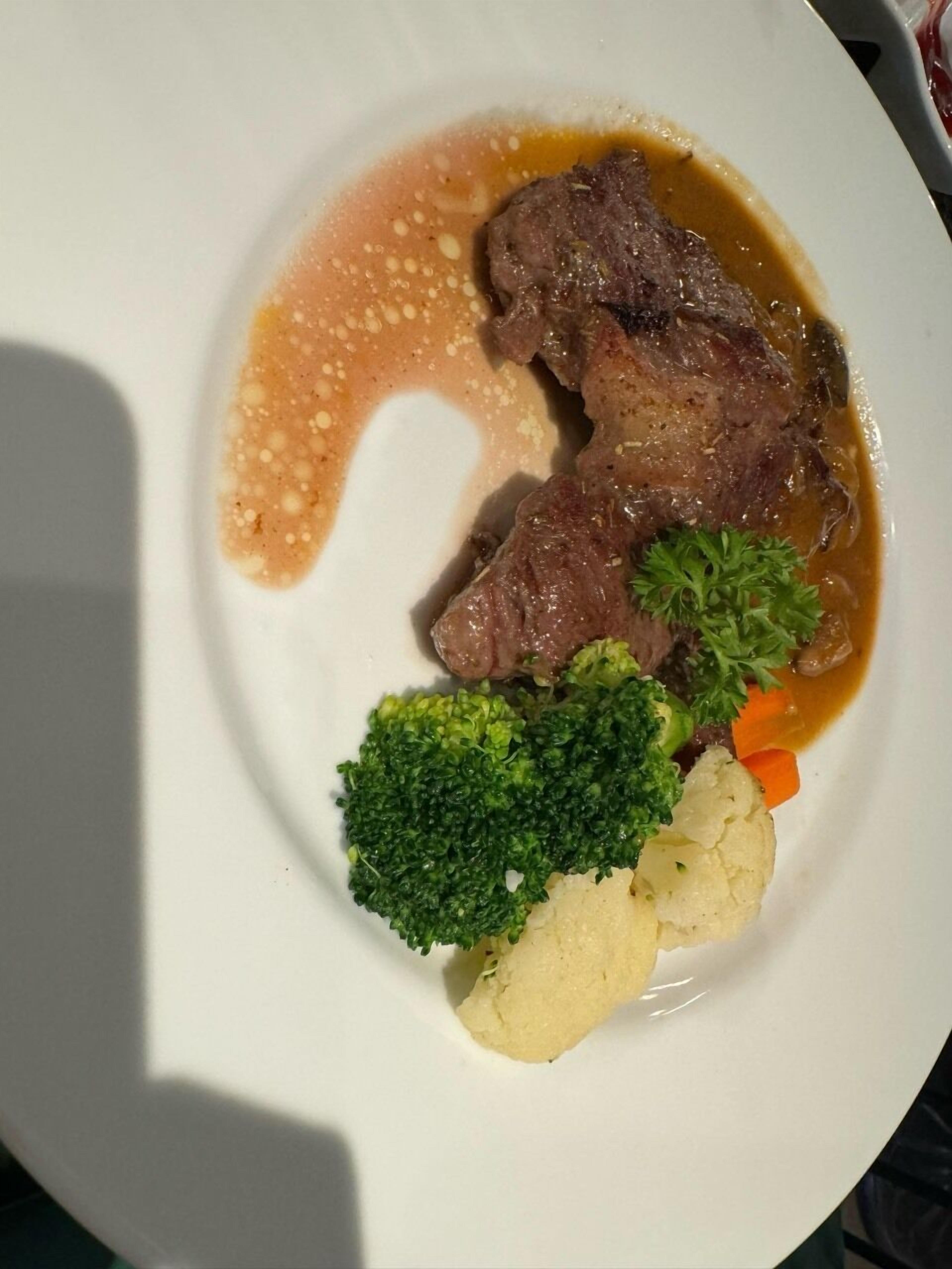 A plate with beef, broccoli, carrots, and cauliflower.